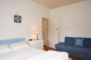 a bedroom with a bed and a blue couch at Dinghy s Rest in Queenscliff