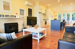 a living room with a couch and a tv and a table at Dinghy s Rest in Queenscliff +7 photos