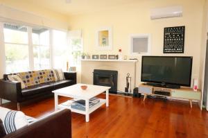 a living room with a fireplace and a tv at Dinghy s Rest in Queenscliff