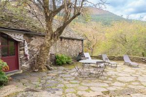 a patio with a table and chairs and a tree at Ecogîte nature de bieisses in Quézac