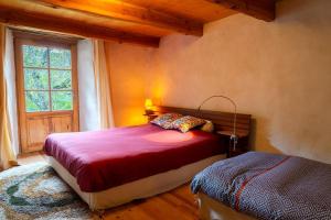 a bedroom with a red bed and a window at Ecogîte nature de bieisses in Quézac