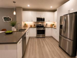 a kitchen with white cabinets and a stainless steel refrigerator at Universal Stays Hollywood-Seconds to Universal Studios in Los Angeles