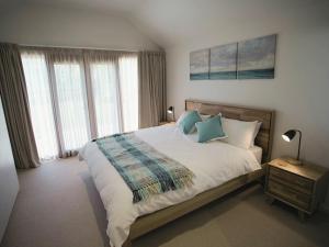 a bedroom with a large bed with blue pillows at Galway Cottage in Queenscliff +15 photos