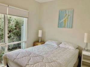 a white bedroom with a bed and a window at Glan Mor in Queenscliff