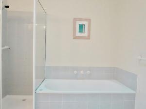 a bath tub in a bathroom with a shower at Glan Mor in Queenscliff