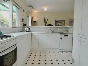a kitchen with white cabinets and a black and white tile floor at Glan Mor in Queenscliff