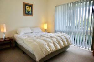 a bedroom with a bed with white sheets and a window at Glan Mor in Queenscliff