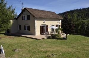 a white house with a deck and a yard at La parrot en margeride in Pierrefiche