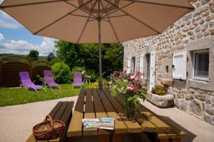 a wooden picnic table with an umbrella and flowers at La maison de clémence 6 personnes in Mialanes