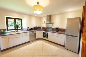 a large kitchen with white cabinets and a refrigerator at Gîte du boy 8 personnes in Lanuéjols