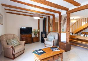 a living room with two chairs and a tv at Gîte du boy 8 personnes in Lanuéjols