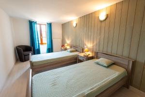 a bedroom with two beds and a chair and a window at Gîte du boy 8 personnes in Lanuéjols
