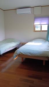 a bedroom with two beds and a window at 民泊kururu 個室 鍵付き朝パン付きライダー用ガレージ有り in Nishidani +6 photos