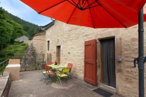 a patio with a table and chairs and a red umbrella at Le gite de granade in Barjac