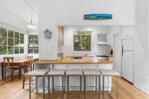 a kitchen with white walls and a counter with bar stools at Lochaber in Point Lonsdale