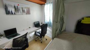 a bedroom with a desk with a computer and a chair at Kochimoto Guesthouse in Baguio