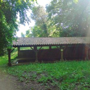 a wooden pavilion with a roof in the grass at Studio Indépendant au calme in Cugand
