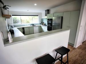 a kitchen with a counter and two stools at Lonsdale on Glaneuse in Point Lonsdale +3 photos