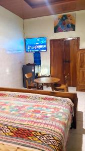 a bedroom with a bed and a table and a tv at Kubumade in Sanur