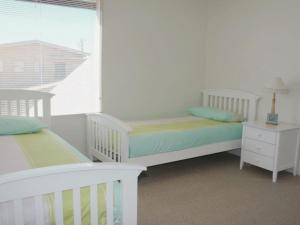 a white bedroom with two beds and a window at Lonsdale Shores in Point Lonsdale