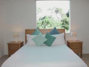 a bedroom with a white bed with blue pillows at Lonsdale Shores in Point Lonsdale