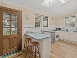 a kitchen with white cabinets and a island with two bar stools at Maison Cottage in Queenscliff +7 photos
