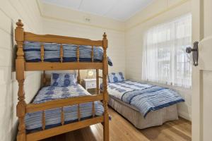 a bedroom with two bunk beds and a window at Maison Cottage in Queenscliff