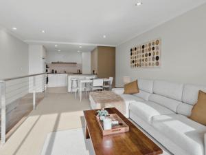 a living room with a white couch and a table at Marley s Place in Queenscliff +3 photos