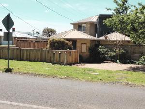 a house with a wooden fence in a yard at Monrepos in Point Lonsdale