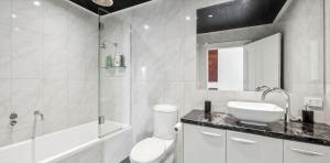 a white bathroom with a sink and a shower at Penthouse Ozone in Queenscliff