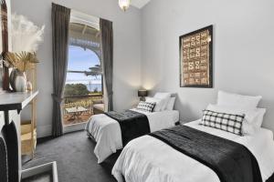 two beds in a room with a balcony at Pelicans at the Ozone in Queenscliff