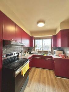 a kitchen with red cabinets and a stove top oven at TORONTO Midtown HomeHaven in Toronto