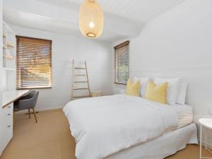 a white bedroom with a white bed and a desk at Ripview in Point Lonsdale