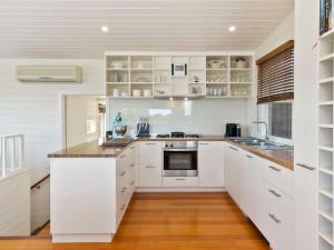 a kitchen with white cabinets and a wooden floor at Ripview in Point Lonsdale