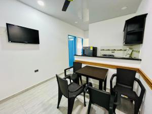 a dining room with chairs and a table and a television at Apartahotel Dazuwi in Doradal