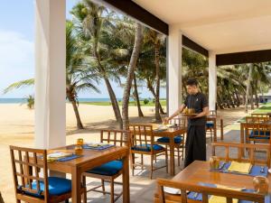 a man standing at a table in a restaurant on the beach at Jetwing Sea in Negombo