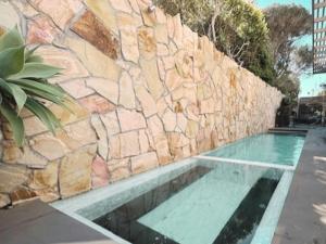 a swimming pool next to a stone wall at Sand Dunes in Point Lonsdale