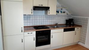 a kitchen with white cabinets and a sink and a stove at Apartment Jackie 2 in Bielefeld