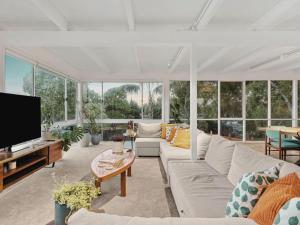 a living room with a white couch and a tv at The Springs in Point Lonsdale