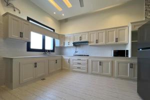 a large kitchen with white cabinets and a window at هلا شاليه اتين in Salalah