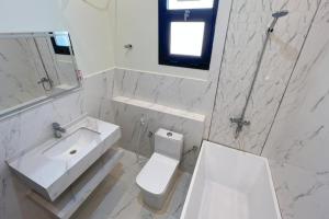 a white bathroom with a sink and a toilet at هلا شاليه اتين in Salalah