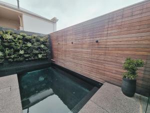 a swimming pool in front of a wall with plants at Stella on Stevens in Queenscliff