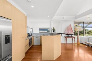 a kitchen with white walls and wooden floors at The Beach House in Point Lonsdale +11 photos
