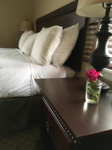 Cama con almohadas blancas y mesa con lámpara en Colts Neck Inn Hotel, en Colts Neck