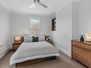 a white bedroom with a bed and a window at The Scoop in Queenscliff
