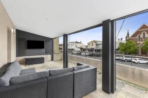 a living room with a couch and large windows at The Scoop in Queenscliff