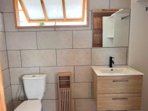 a bathroom with a toilet and a sink and a window at Hakamanu Lodge in Tikehau