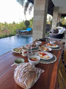 a wooden table with plates of food on it at Maya Villa in Candidasa