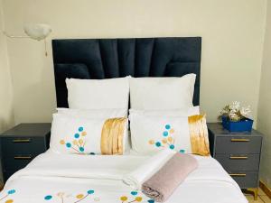 a bed with white pillows and a black headboard at Smileys accomodation in Standerton +3 photos