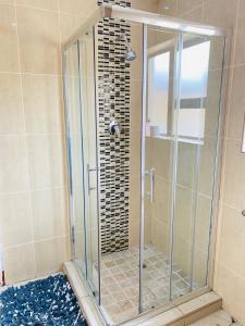 a shower with a glass door in a bathroom at Smileys accomodation in Standerton